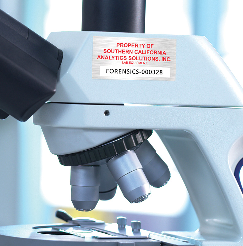 Close-up of a microscope showing asset label with variable data.