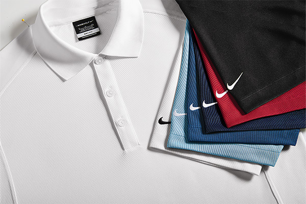 Stacked group of nike polos in several color all showing the iconic Nike swoosh.