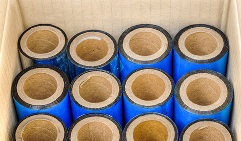 label-products-thermal-solutions-label-ribbons-premium-wax-maverick-printing Group of blue wax thermal transfer ribbons in a box.