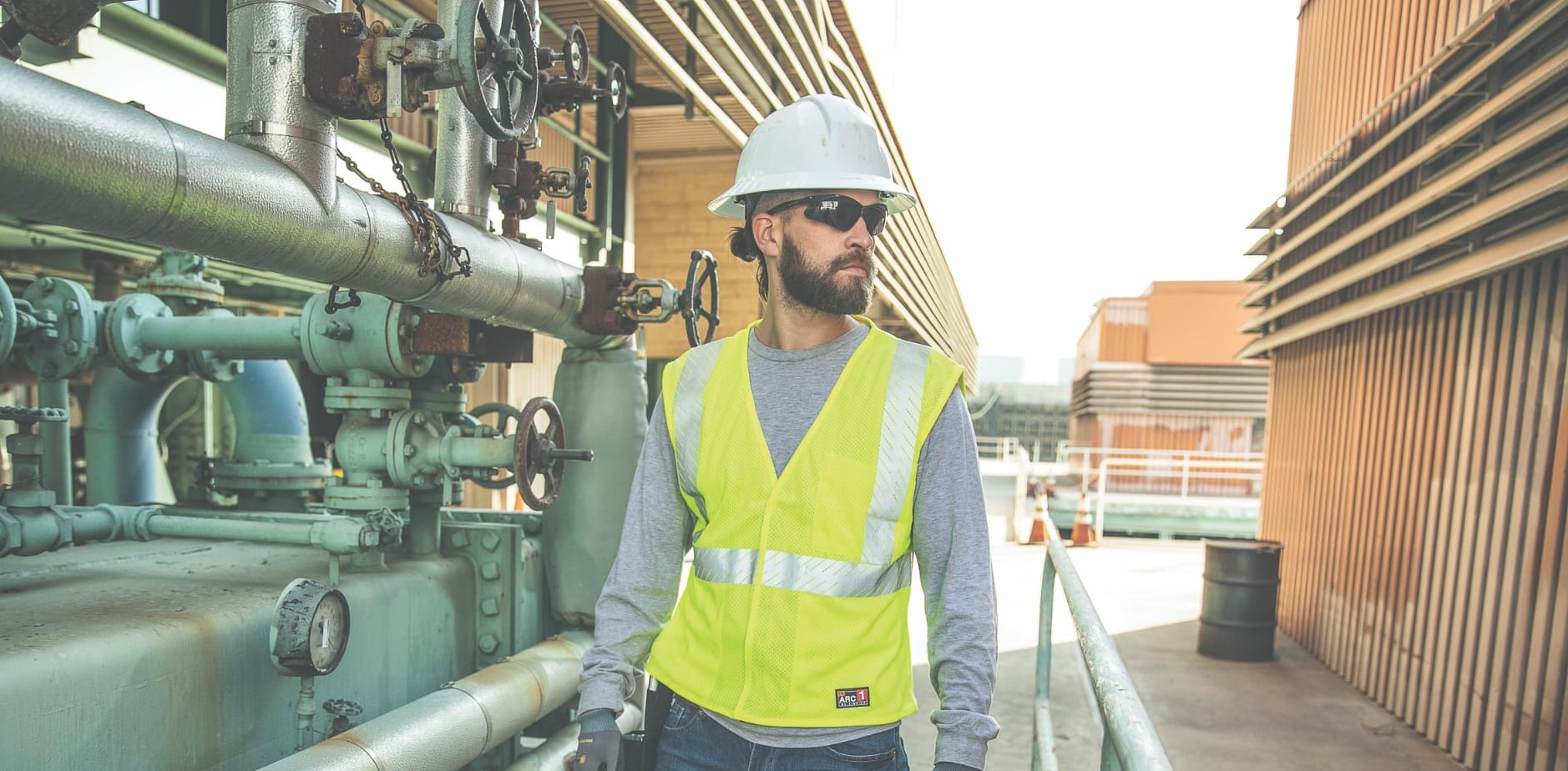 Person wearing high visibility safety vest in an outdoor industrial environment.